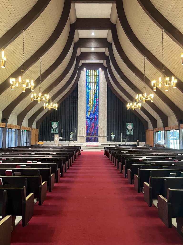 Photo of the sanctuary; it has red carpet and dark wooden pews